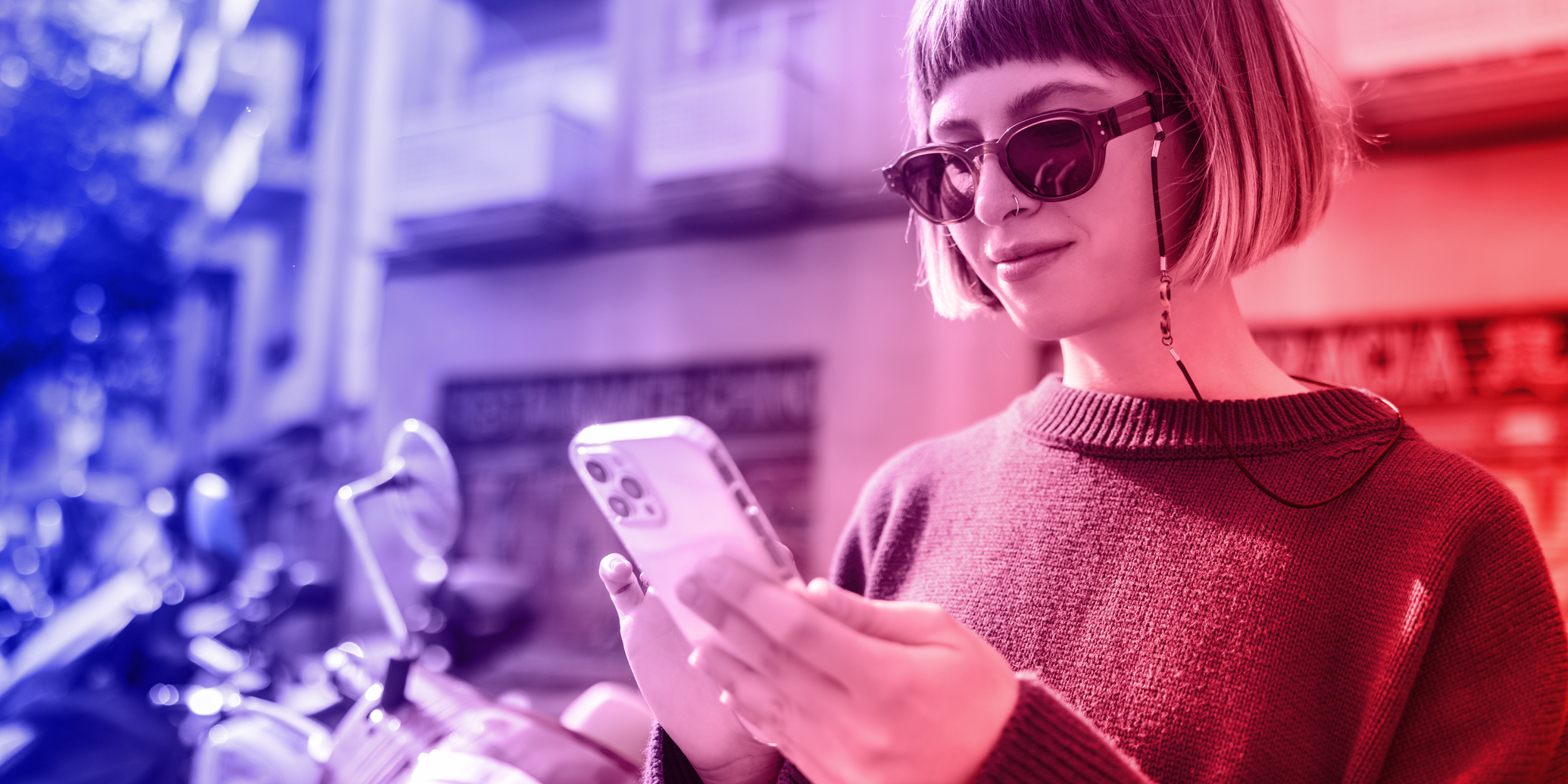 Revolutioniere dein Marketing auf TikTok: Eine junge Frau steht mit ihrem Handy auf ihrem Balkon.