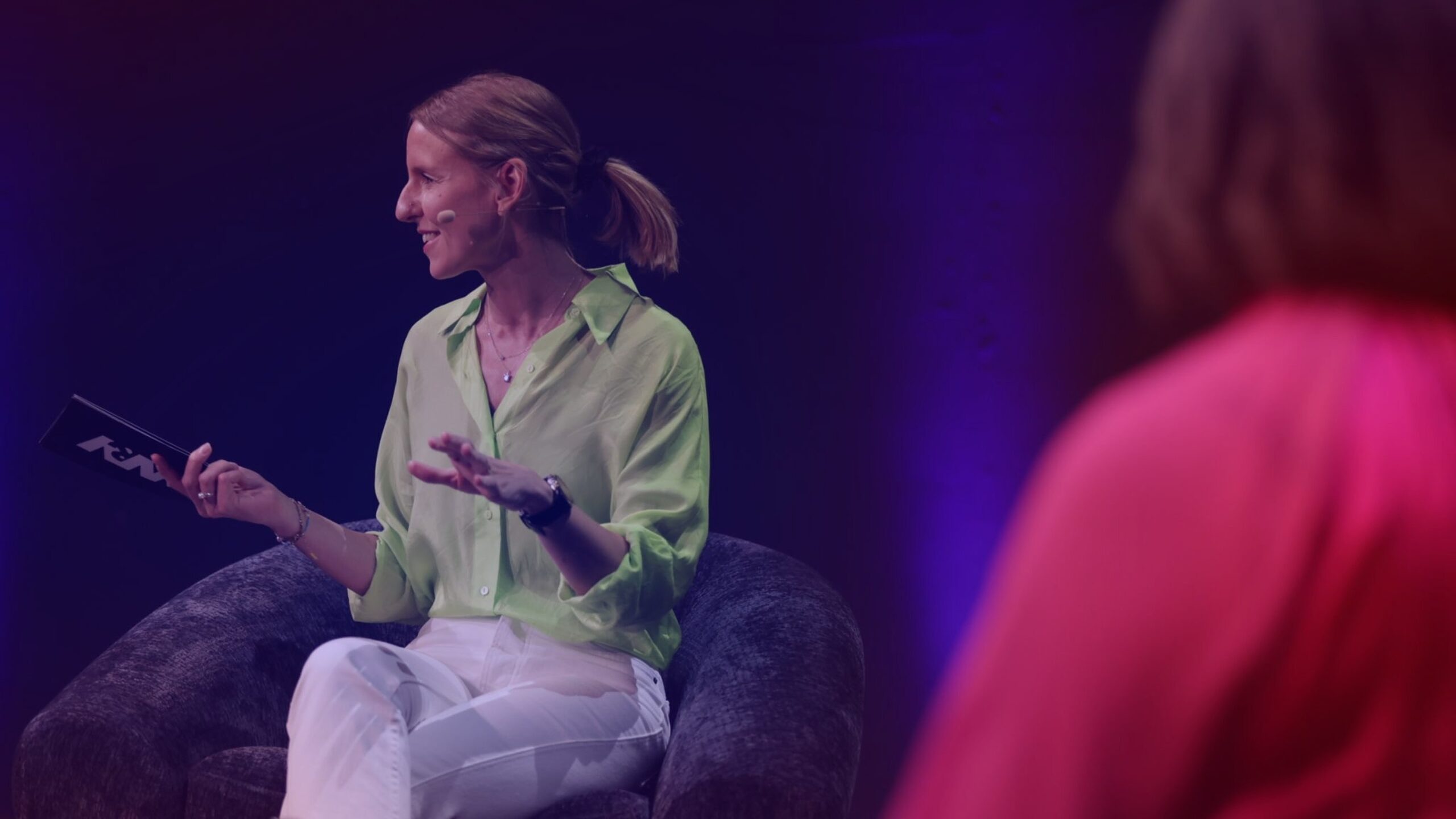 Brand Relevance: Panel with DMEXCO host Verena Gründel Brand Relevance: DMEXCO host Verena Gründel, wearing a bright green shirt, speaks on stage during a panel discussion.